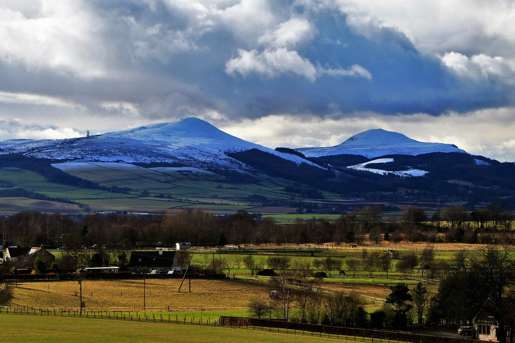 Scenic view of a mountain range with snow under a cloudy sky, with a valley in the foreground.
