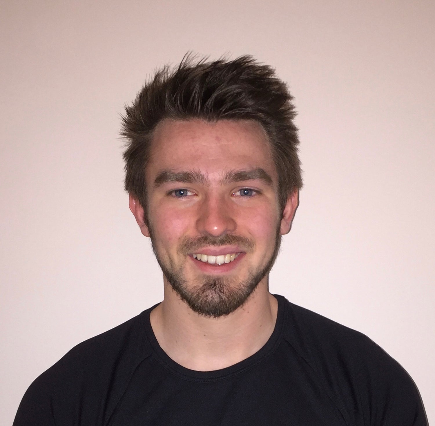 Tour guide with a beard wearing a black shirt against a plain background